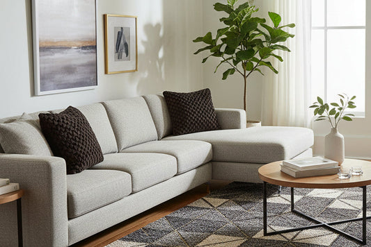 Gray chair with a textured black pillow on a light wooden floor.