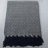A woven throw blanket and matching square pillow set in a gray and white chevron pattern, with the blanket featuring dark navy fringe at the bottom, displayed on a light gray surface.