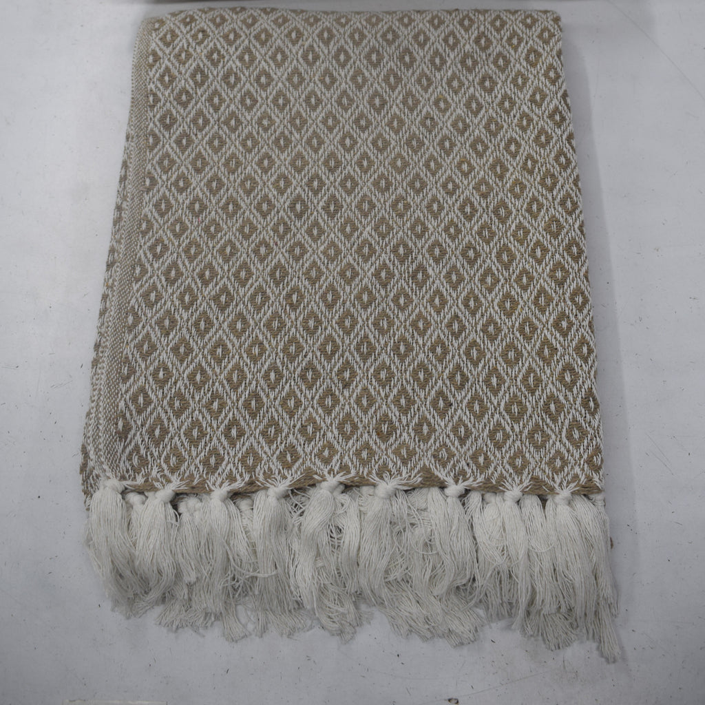 A woven throw blanket and matching pillow set in beige and white with a repeating diamond pattern and fringed edges, laid flat on a light gray surface.
